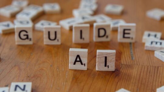 Wooden letter tiles spelling GUIDE and AI on a wooden table