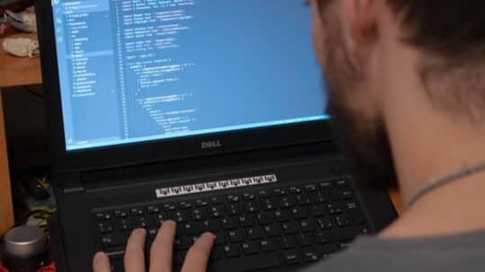 Developer seen over the shoulder, working on code on a laptop